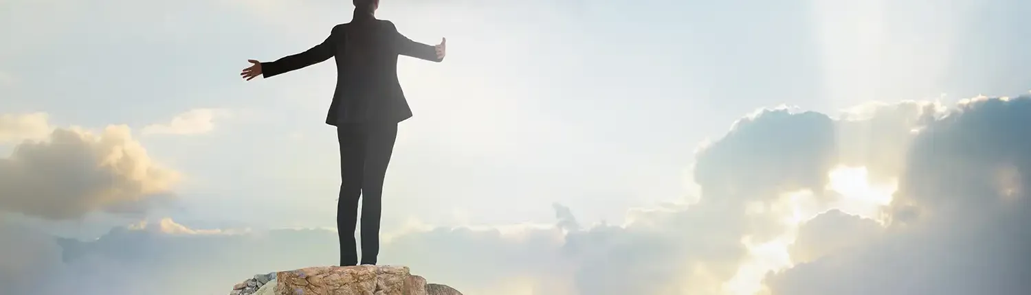 Career Coaching with Ann Vanino - Image of a Business Women on the Top of a Mountain, Arms Outstretched