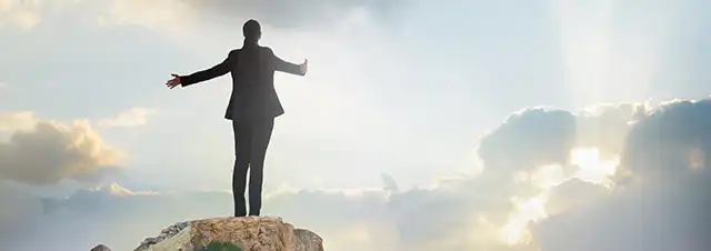 Career Coaching with Ann Vanino - Image of a Business Women on the Top of a Mountain, Arms Outstretched