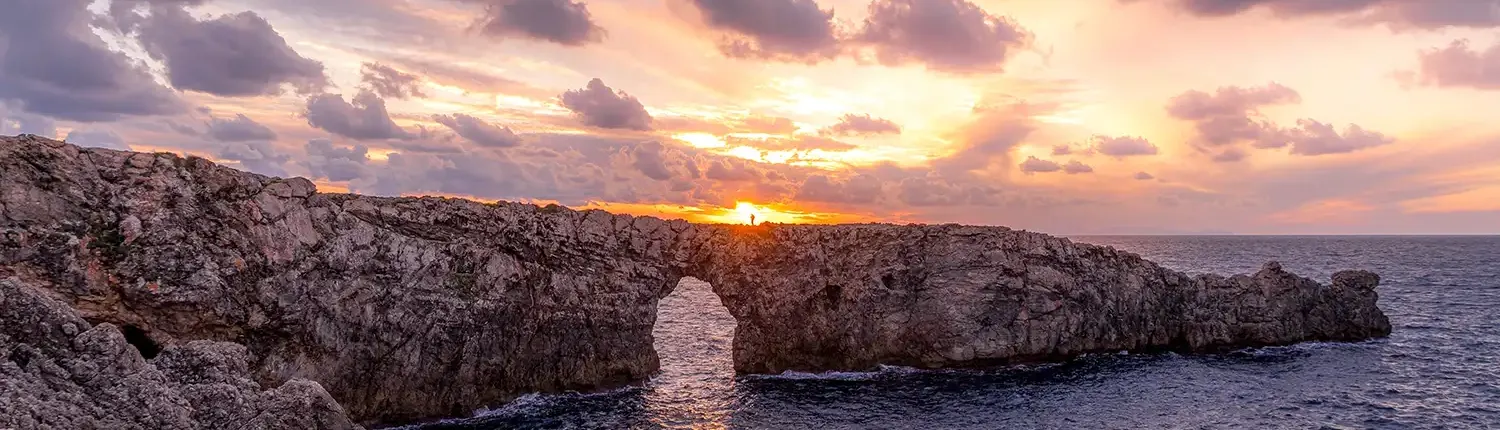 Coaching for a New Era with Ann Vanino, Image of a natural arch on a promontory, with the sun breaking through